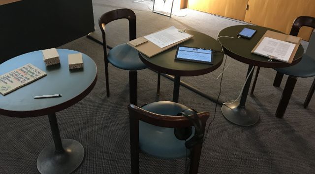 Drei runde Tische mit iPads, Kopfhörern, Notizmaterial