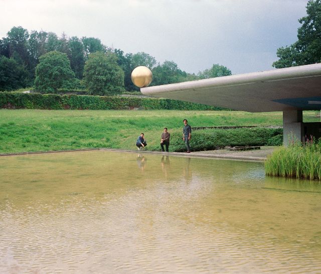 Schnellertollermeier posiert am Teich, über ihnen ein Dach mit einer goldenen Kugel