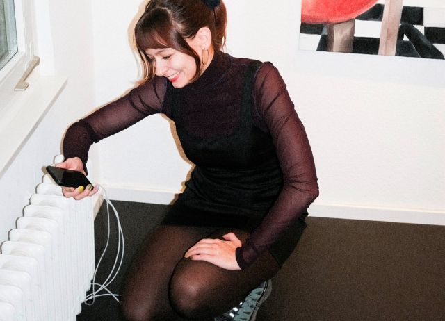 Frau am Telefon, neben einem Radiator 