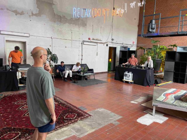 Menschen in einer Halle arbeiten an Mischpult, an Computern und hören offensichtlich Sound