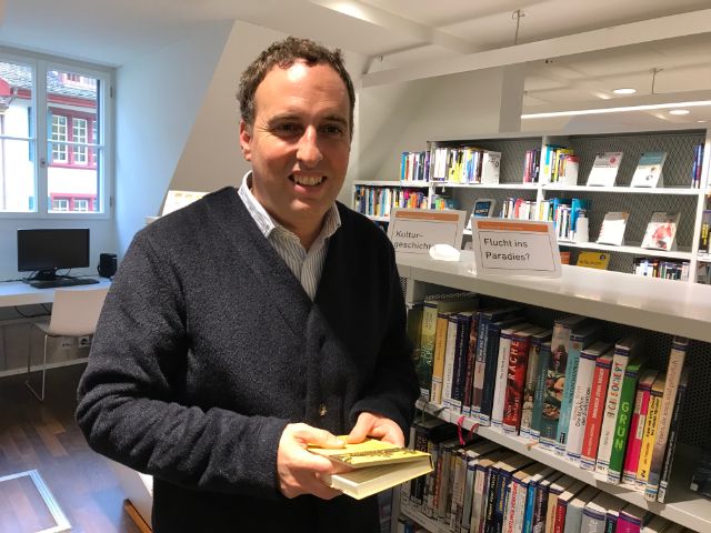 Ein Mann mit einem Buch in der Hand steht in der Bibliothek