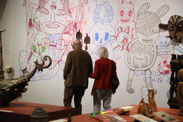 zwei ältere Menschen spazieren im Museum und betrachten ein Wandkunstwerk