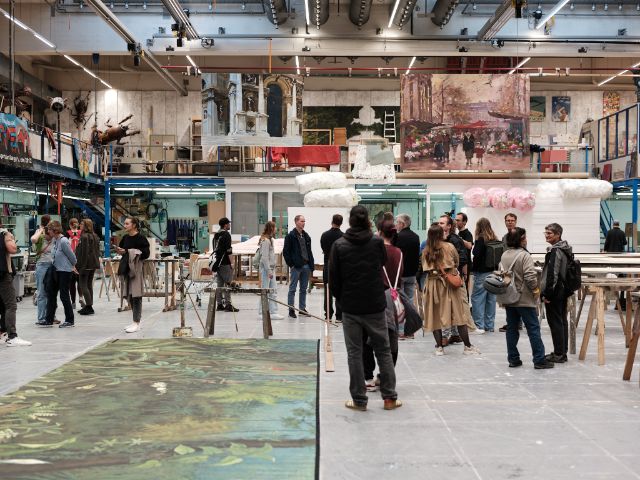 Ein grosser Raum mit vielen Menschen, Theaterkulissen und Werkstatt-Zubehör