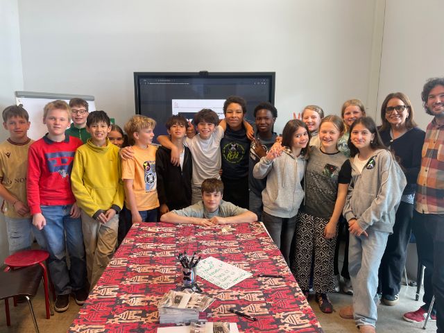 Eine Klasse mit 12/13-jährigen Schüler:innen posieren, rechts von ihr zwei Lehrpersonen