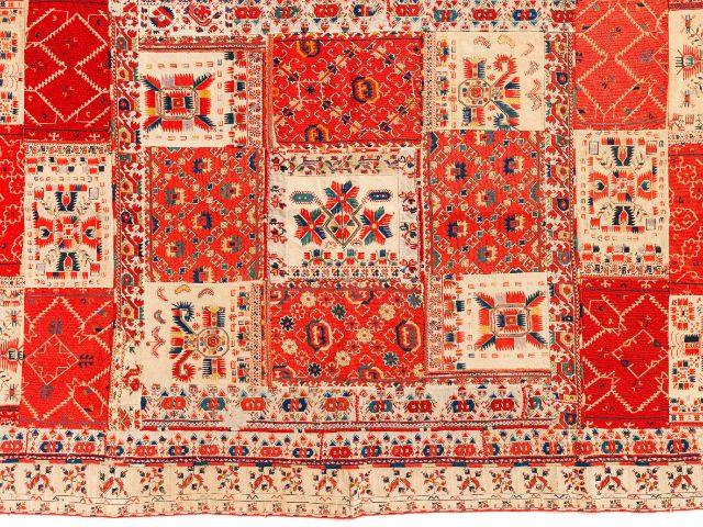 Detailansicht eines rot-weissen Teppichs mit vielen Stoffmustern