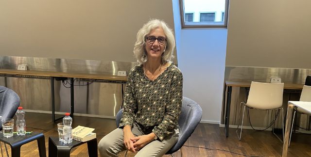 Eine Frau mit halblangen weissen Haaren und schwarzer Brille