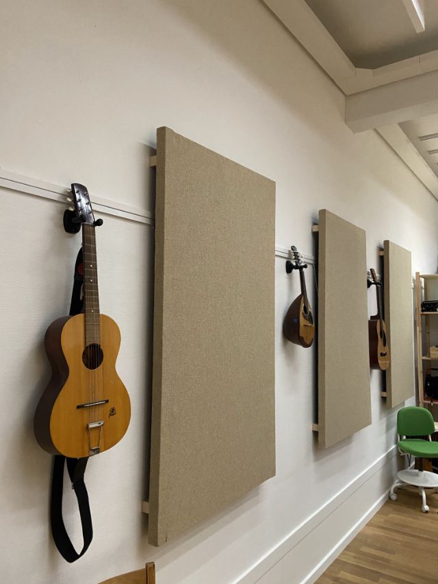 Viele Instrumente, wie Gitarre oder Ukulele hängen an der Wand im Kursraum.