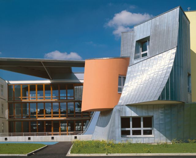 Ein aussergewöhnlicher Bau zeigt eine schräge Fassade in metallsilbern und orange