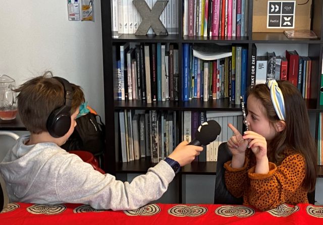 Zwei Kinder der X-Kids interviewen sich gegenseitig.