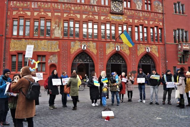 Menschen stehen vor dem Rathaus in Basel mit ukrainischen Flaggen.
