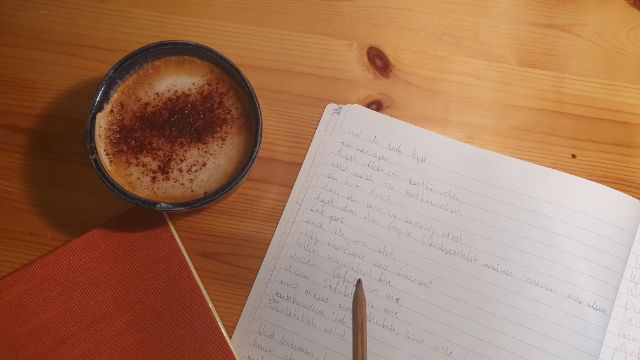 Cappuccino und handgeschriebene Notizen auf einem Holztisch