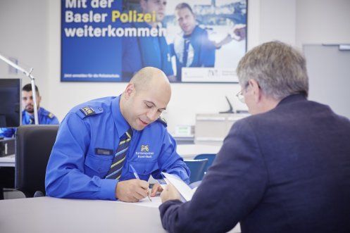 Ein Mitarbeiter der Kantonspolizei nimmt einen Fragebogen von einem Zivilisten entgegen.