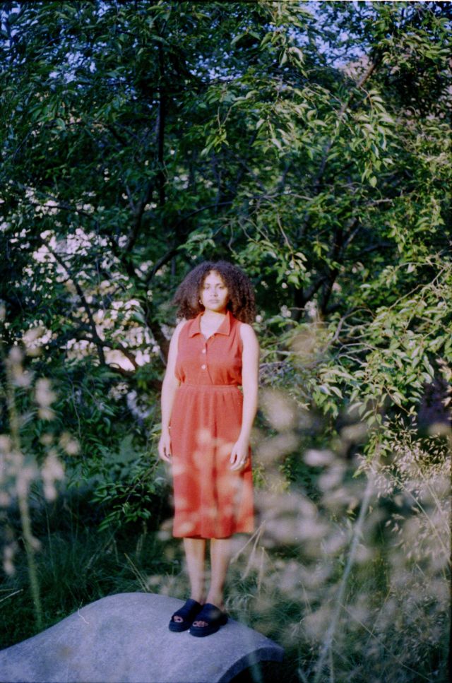 Eine junge Frau im Kleid zwischen Vegetationen