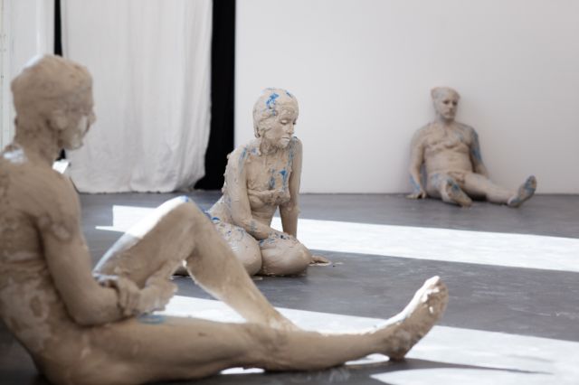 Zu sehen sind drei Körper welche wie Skulpturen im Raum sitzen