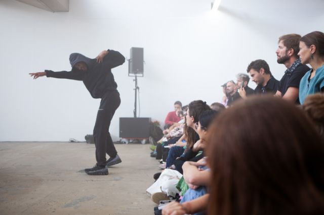 Eine in schwarz gekleidete Figur tanzt vor Publikum