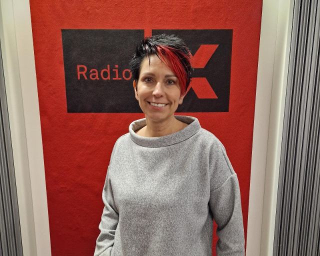 Sandra Sollberger steht in unserem Studio vor dem Radio X Logo.