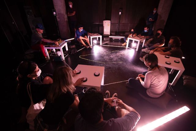 menschen sitzen im kreis und lauschen einer experimentellen elektronischen Klang Performance