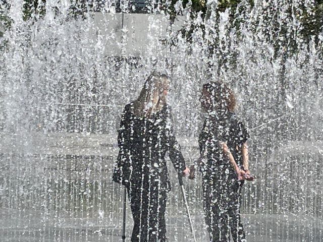 Zwei Frauen stehen in der Wasserskulptur von Jeppe Hein