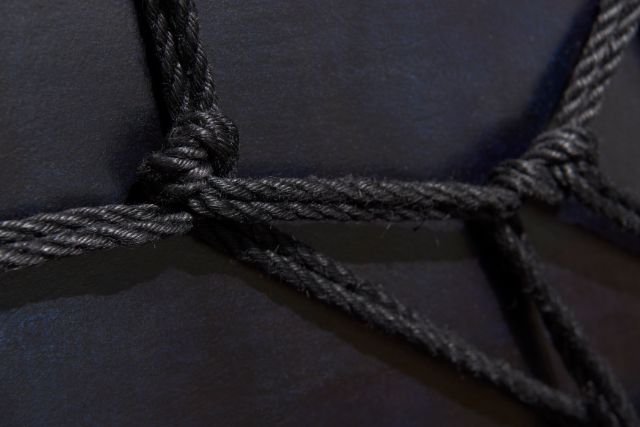 Ein schwarzes, zugebundenes Seil auf schwarzem Hintergrund