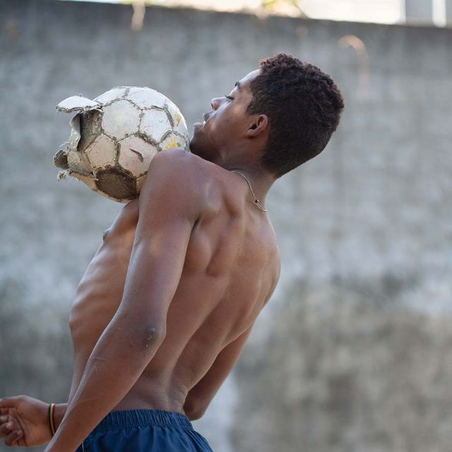 Ein Jugendlicher spielt oben ohne Fussball in den Favelas in Brasilien.