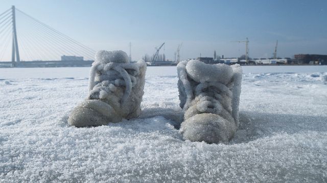 Ein paar Schuhe sind vereist und stehen im Schnee.