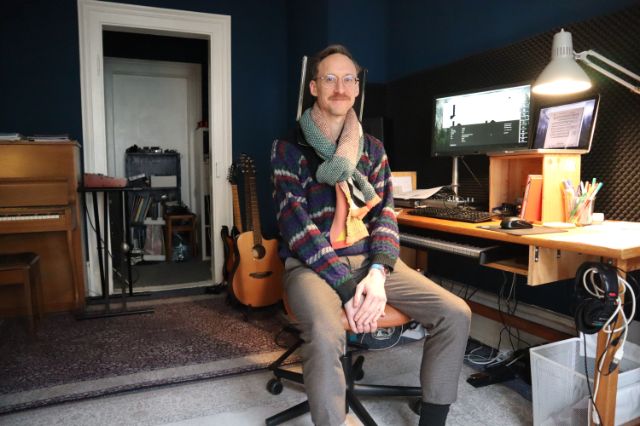 Ein Mann sitzt in einem Raum mit Musikinstrumenten