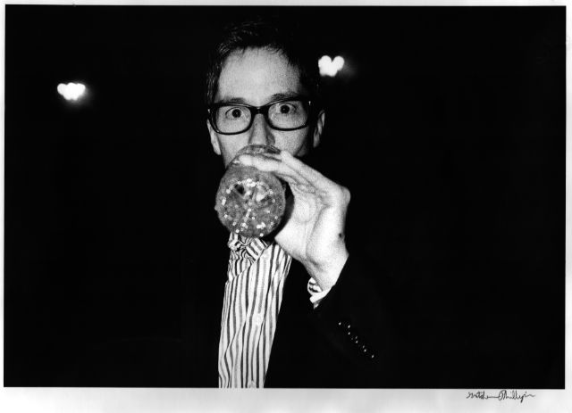 schwarz-weiss fotografie einer frau mit brille und getränk