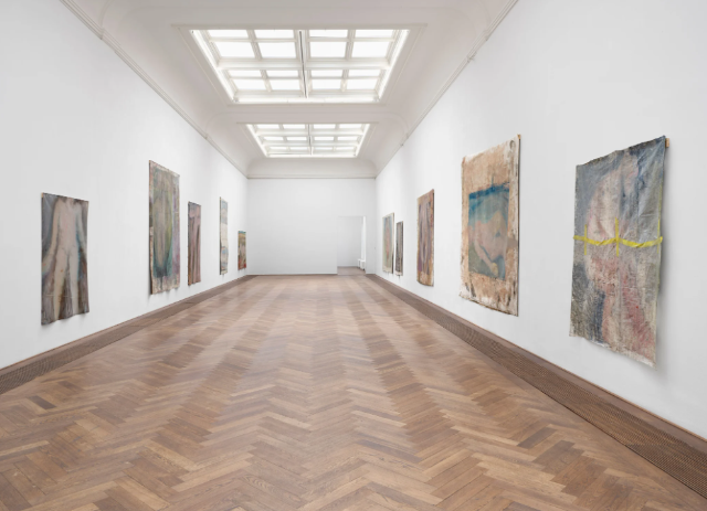Ansicht des Ausstellungsraum. Links und rechts sind grossformatige Bilder nackter Körper.