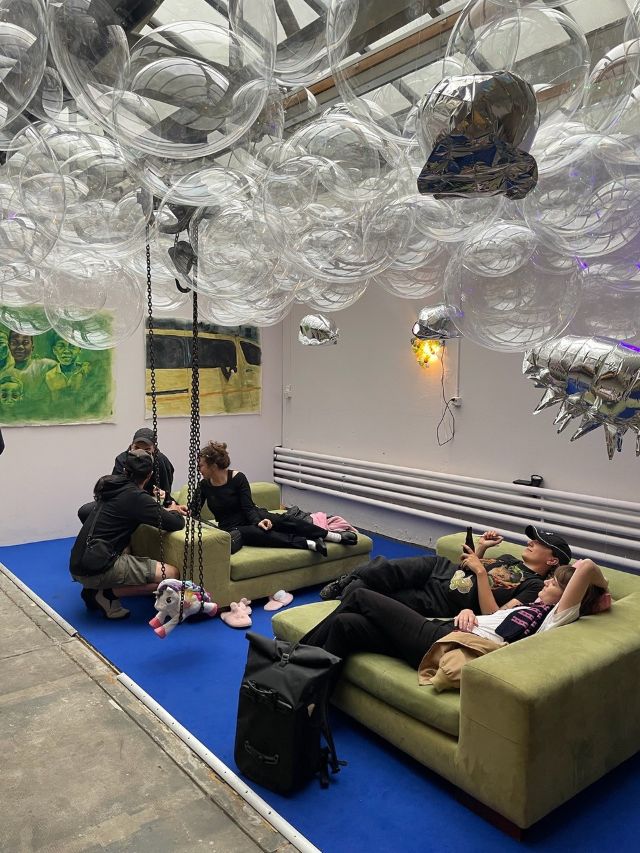 Blauer Teppich, Grüne Sofas, Menschen auf den Sofas, Balone in der Luft, 