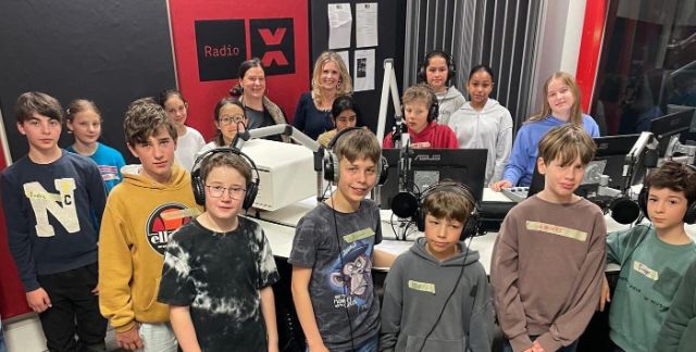 Eine besammelte Schulklasse mit zwei Lehrpersonen im Studio von Radio X