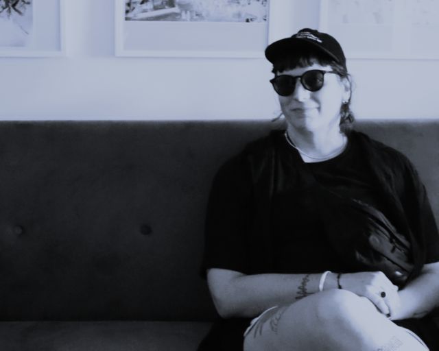 eine person mit sonnenbrille sitzt und schaut zur kamera
