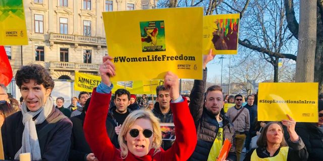 Eine Demonstration in der Schweiz mit Menschen, die gelbe Transparente hochhalten, worauf #WomenLifeFreedom steht