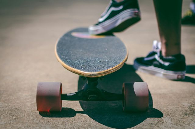 Ein Longboard mit Skatebordschuhen unterwegs auf einer Strasse