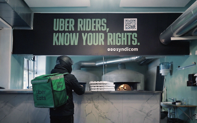 Ein UberEats Rider nimmt eine Pizza Bestellung in einem Restaurant entgegen.