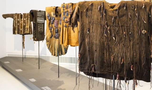 Aufgehängte Kleider im Museum, reich verziert und behangen mit Naturmaterialien