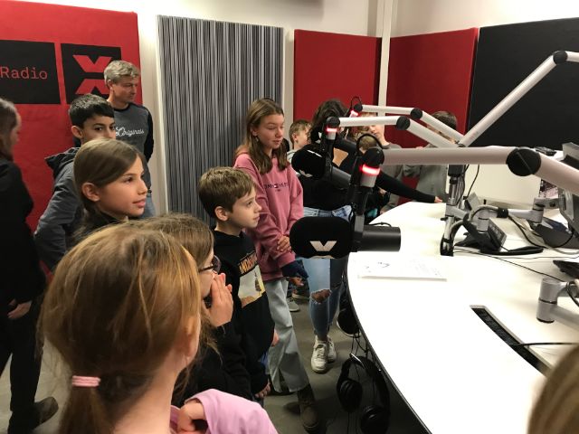 Viele Kinder schauen gespannt und sprechen ins Mikrofon im Aufnahmestudio 